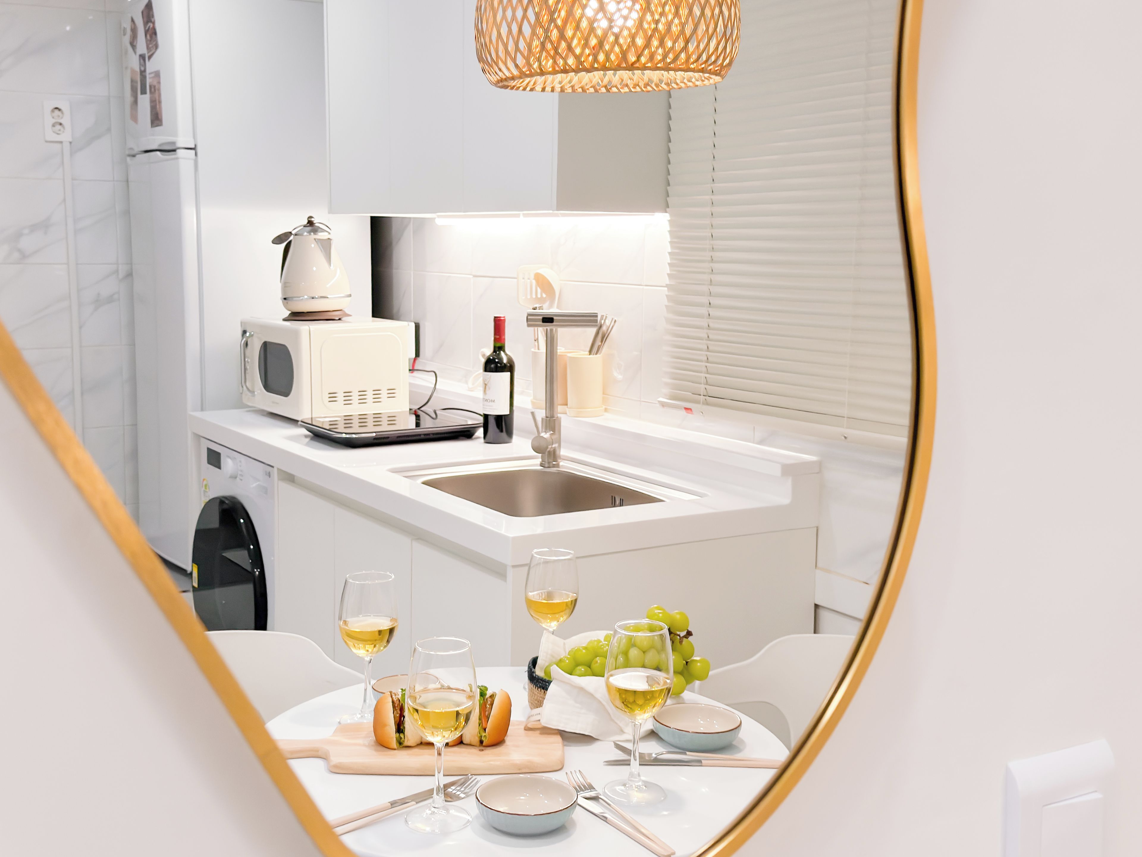 A modern kitchen with a built-in island, a microwave, a wine bottle, and a dining area with a table set for two.