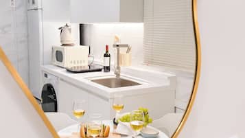 A modern kitchen with a built-in island, a microwave, a wine bottle, and a dining area with a table set for two.