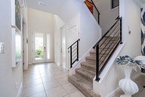 A staircase with a black railing, a white wall with a door, and a tiled floor. - Near Disney Private Pool Bella Vida Resort (Kissimmee)