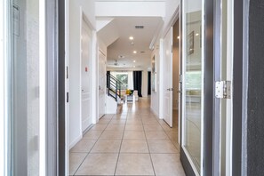 A hotel hallway with a tiled floor, a staircase, and a door leading to a room. - Near Disney Private Pool Bella Vida Resort (Kissimmee)