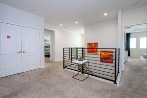 A hallway with a white door, a metal partition, and two paintings on the wall. - Near Disney Private Pool Bella Vida Resort (Kissimmee)