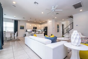 A modern living room with a white sofa, a dining area with a table and chairs, and a kitchen in the background. - Near Disney Private Pool Bella Vida Resort (Kissimmee)