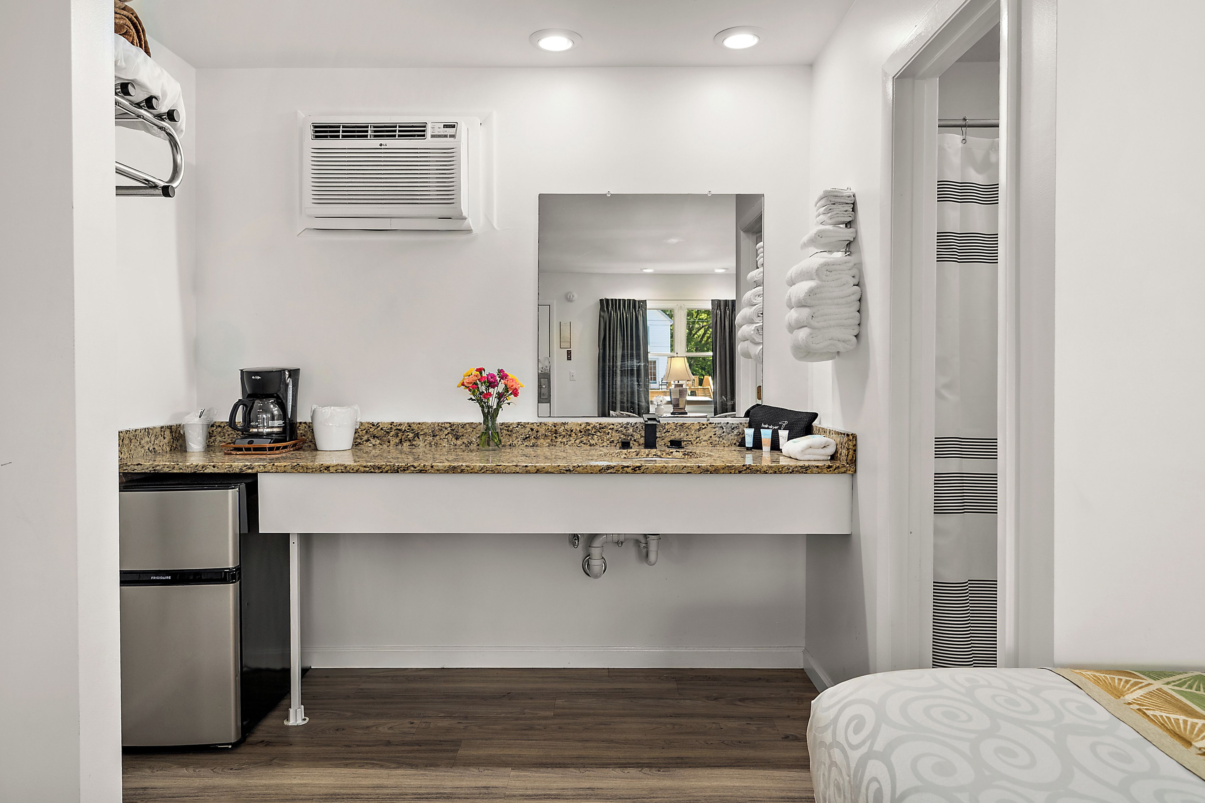 A compact kitchenette with a built-in refrigerator, a coffee maker, and a sink with a granite countertop.
