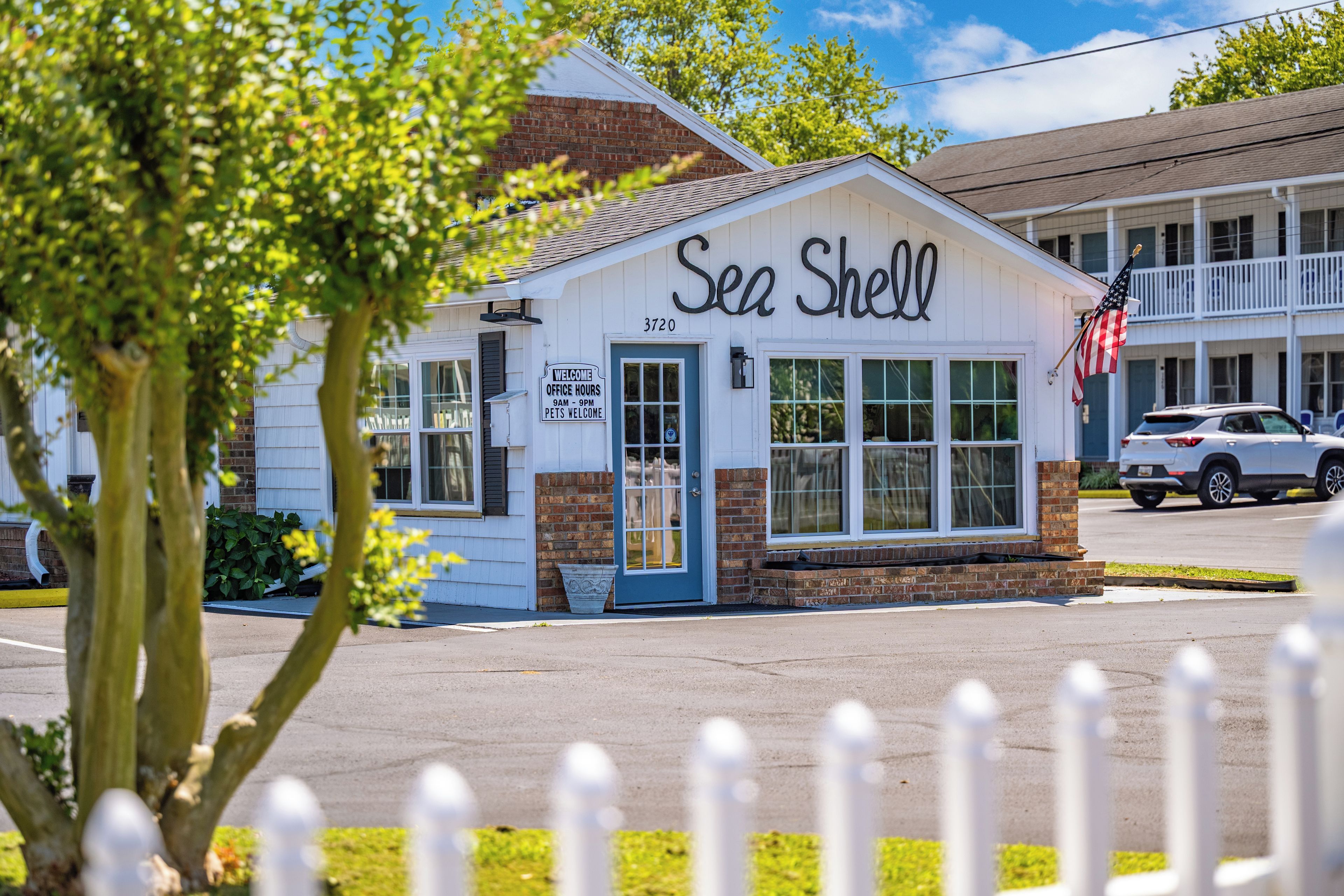 A white building with a sign reading 'Sea Shell' and a small American flag.