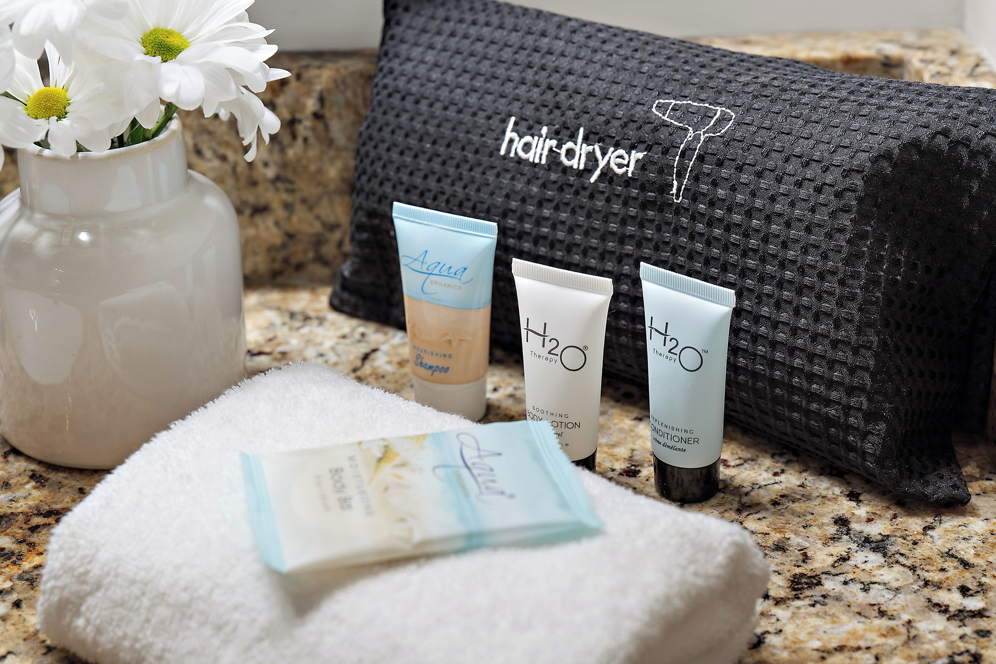 A bathroom with a towel, a hairdryer, and toiletries on a countertop.