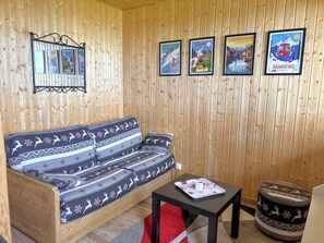 Ein Zimmer mit Holzvertäfelung, einem Sofa, einem kleinen Tisch mit Tablett und gerahmten Bildern an der Wand.