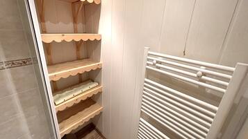 A narrow walk-in closet with wooden shelves and a white radiator.