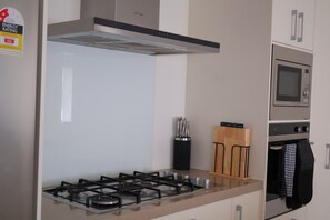 A modern kitchen with a gas stove, a stainless steel range hood, a microwave, and a knife block. - Beauty near the Ocean spacious four-bedroom home (New Plymouth)