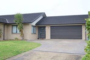 A residential house with a garage, a driveway, and a small lawn. - Beauty near the Ocean spacious four-bedroom home (New Plymouth)