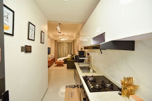 Cocina moderna con estufa integrada, zona de comedor con sofá y sala de estar con cama.