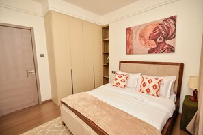 Un dormitorio con cama, armario, un cuadro y mesita de noche.