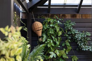 Una pèrgola de fusta amb plantes trepadores i una cistella penjant.