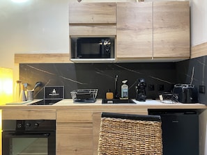 A modern kitchen with wooden cabinets, a microwave, a coffee maker, and a dishwasher. - An air-conditioned retreat in the heart of Agde's historic center (Agde)