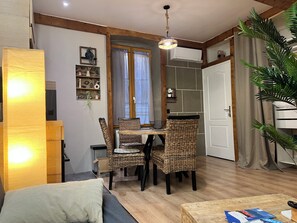 A cozy living room with a dining area, wooden beams, a hanging light fixture, and a potted plant. - An air-conditioned retreat in the heart of Agde's historic center (Agde)