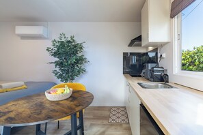 Une cuisine compacte avec un coin repas, une plante en pot et une machine à café.