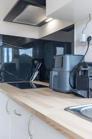 Une cuisine moderne avec un dosseret de carreaux noirs, un four encastré et une machine à café.