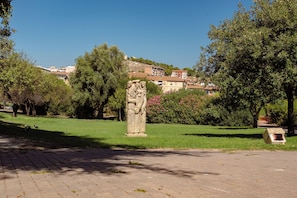 Ein Park mit einer Steinstatue, Bäumen und Gebäuden im Hintergrund.