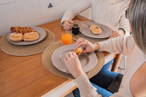 Un tavolo da pranzo con sottopiatti, piatti contenenti dolci, un bicchiere di succo d'arancia e uno smartphone sul tavolo.