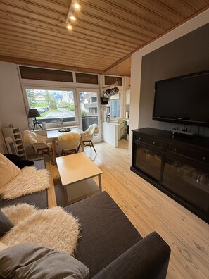 A modern living room with a sofa, a coffee table, and a flat-screen TV. - Cozy vacation rental at Alpendomizil—a great ski resort in the Hochkönig region of Austria (Mühlbach am Hochkönig)