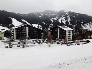 Un hôtel à la façade symétrique, doté de nombreux balcons et disposant d’un parking dans une région montagneuse enneigée.