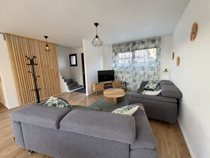 A modern living room with a grey sofa, a wooden coffee table, and a TV. - Across the Fields (Duttlenheim)