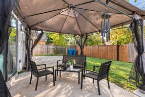 Eine Außenpatio mit überdachter Sitzgruppe, einem Tisch und Stühlen.