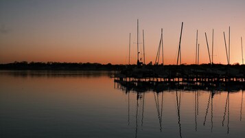 A calm lake at sunset with boats docked at a pier.