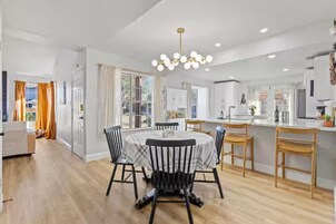 A modern kitchen with white cabinets, a central island, and a dining area with a round table and chairs.