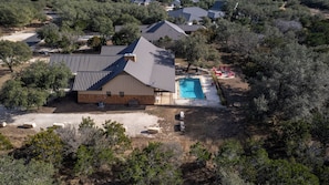 A residential property with a swimming pool, a covered patio, and a large house with a sloped roof. - 19TH Hole: 4  BR, 4.5  BA House in Concan, Sleeps 20 (Concan)