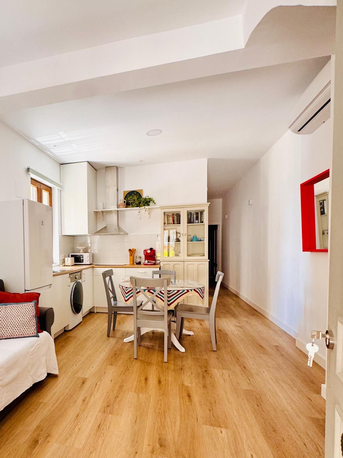 Un espacio habitable compacto con kitchenette, comedor y cama.