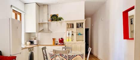Un espacio habitable compacto con kitchenette, comedor y cama.