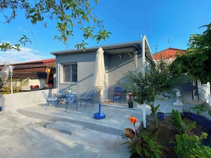 A residential property with a patio area featuring outdoor furniture, a covered seating area, and a small garden with plants and a bird feeder. - Brand new House with Veranda for family 2 minutes from the sea (Agia Triada)