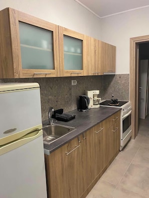 A kitchen with wooden cabinets, a stainless steel sink, a coffee maker, and a stove. - Brand new House with Veranda for family 2 minutes from the sea (Agia Triada)