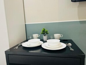 A table set with white dishes, a small potted plant, and a glass of water. - Neu suite Standard Room By Rasbo Galaxy (Kuala Lumpur)