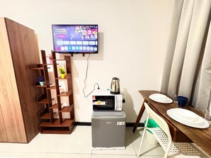 A compact kitchenette with a microwave, a small refrigerator, a coffee maker, and a television mounted on the wall. - Neu suite Standard Room By Rasbo Galaxy (Kuala Lumpur)