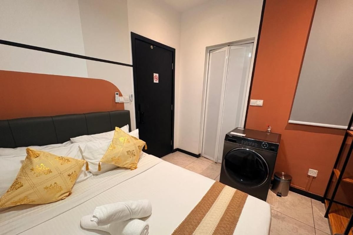 A hotel room with a bed, a washing machine, and a door.
