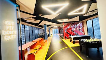 Un gimnasio moderno con equipo de ejercicio, mesa de fútbol y señalización motivacional.