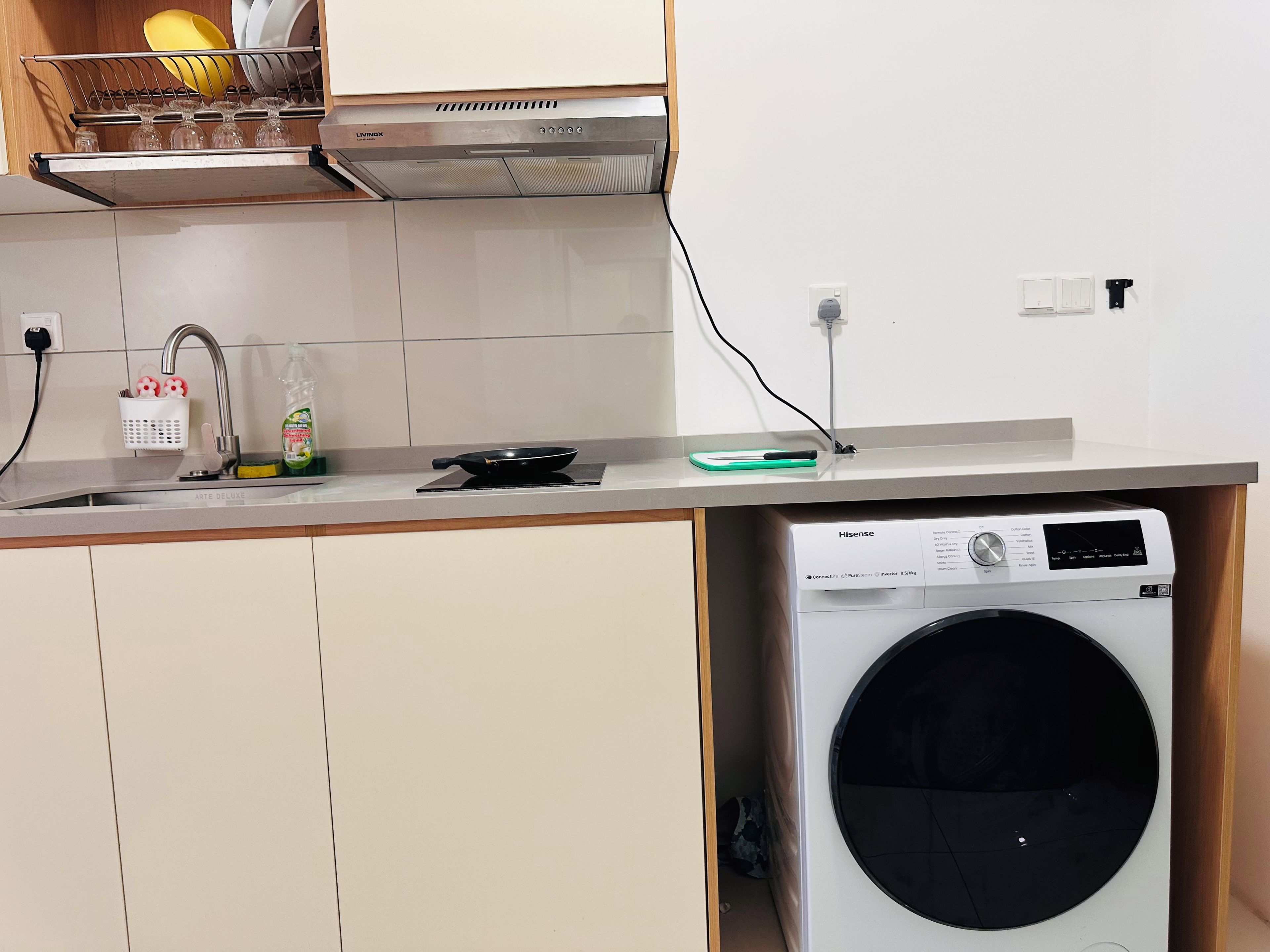Una cocina compacta con lavadora, pileta y encimera.