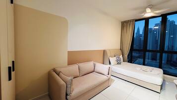 Una habitación de hotel moderna con un ventanal grande, un sofá, una cama y un ventilador de techo.