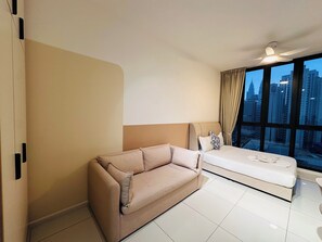 Habitació d'hotel moderna amb una finestra gran, un sofà, un llit i un ventilador de sostre.