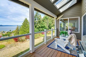 A covered deck with a view of the sea, a chair, and a potted plant. - 4-unit Group Retreat! 2 Hot Tubs & Walk to Beach (Hansville)