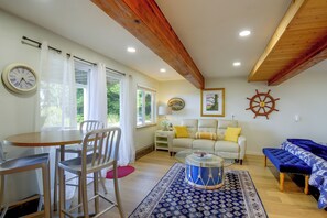 Ein Wohnzimmer mit Essbereich, Holzbalkendecke, einer Uhr und einer Schiffslaugendesigns.