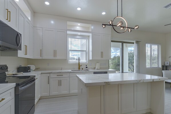 A modern kitchen with white cabinetry, a large island, and a built-in oven.