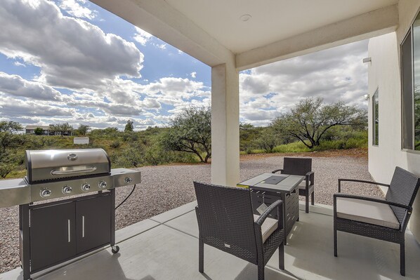 An outdoor patio with a grill, chairs, and a table.