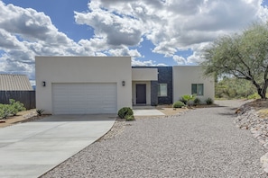 A modern two-story house with a garage, a stone pathway, and a landscaped garden.