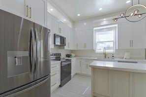 A modern kitchen with stainless steel appliances, white cabinetry, and a central island.
