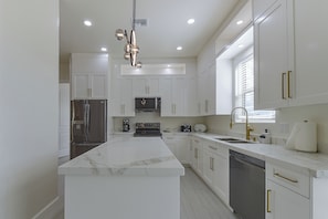 A modern kitchen with white cabinetry, stainless steel appliances, and a marble countertop. - Modern Rio Rico Home Near Nogales & Lake Rec! (Rio Rico)
