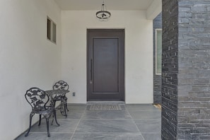 A front door with a dark frame, a small window to the left, and a decorative metal railing in front.