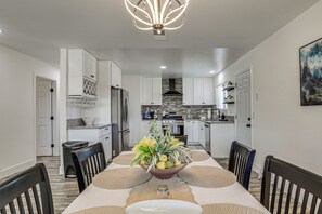 A modern kitchen with white cabinets, a stainless steel refrigerator, and a black stove. - Desert Oasis: Home Near Joshua Tree NP! (Twentynine Palms)
