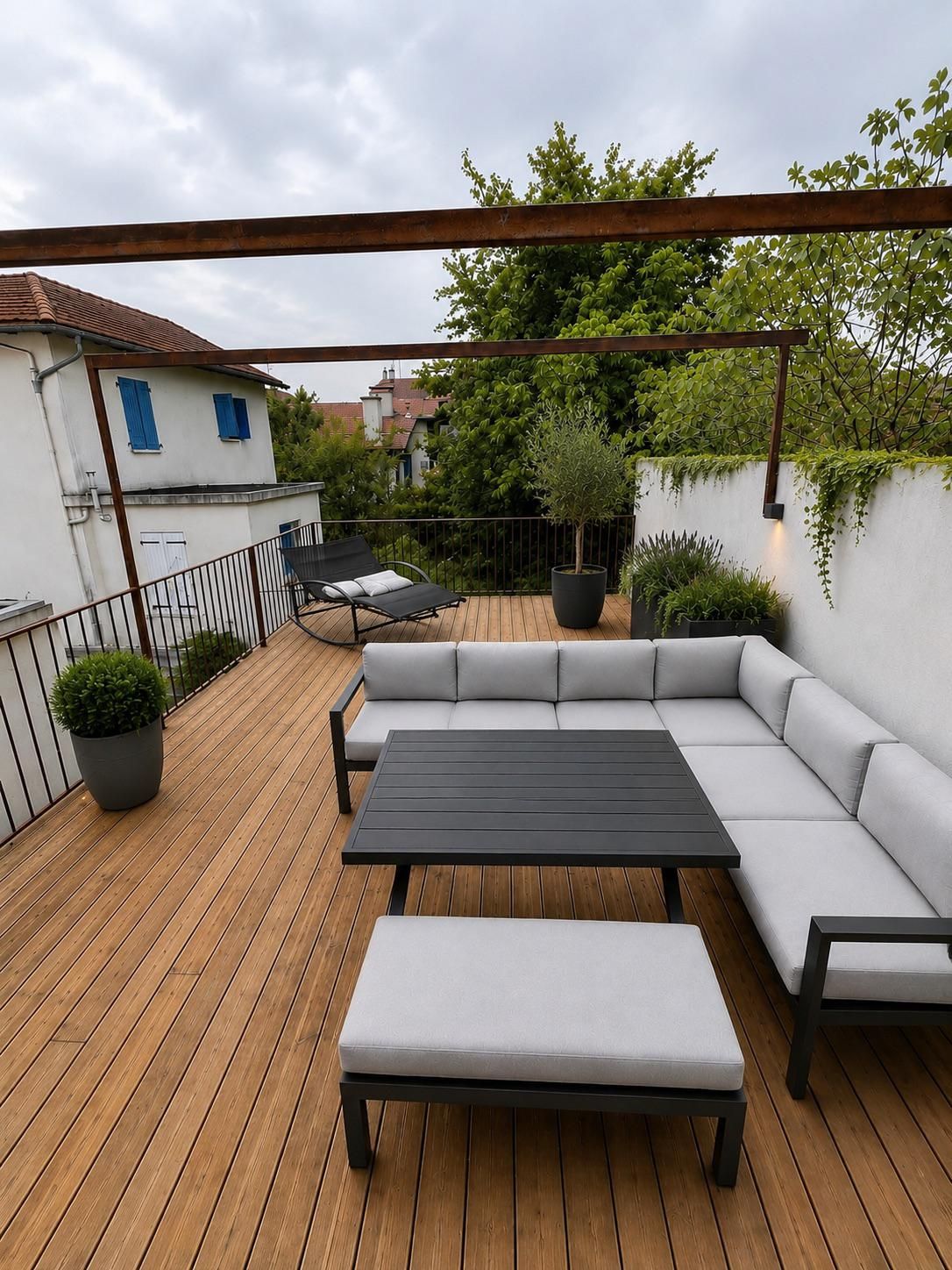 Una terraza de madera con un sofá, una mesa y macetas.